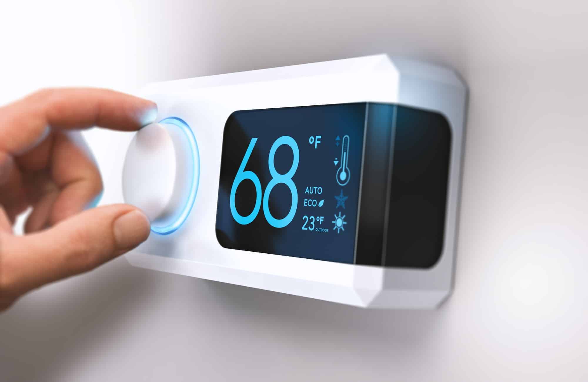 Tourner à main un bouton de thermostat domestique pour régler la température sur le mode d'économie d'énergie. 